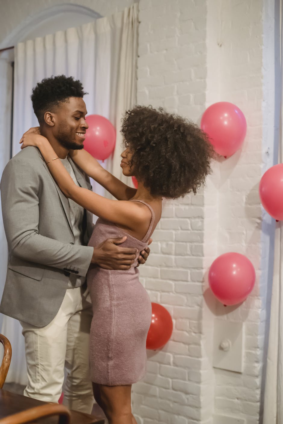 Romantic African American couple in elegant wear embracing & looking at each other, celebrating
