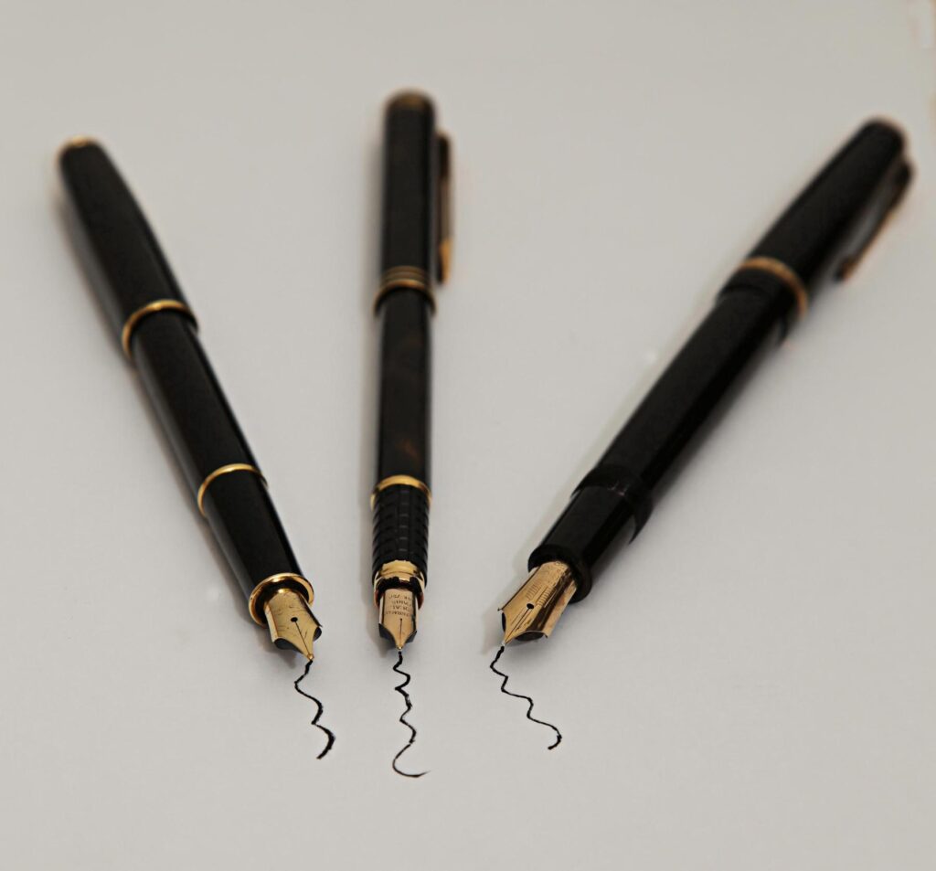 three black pens and a pen on a white background - File:The write thing Project 365(2) Day 12 (43557